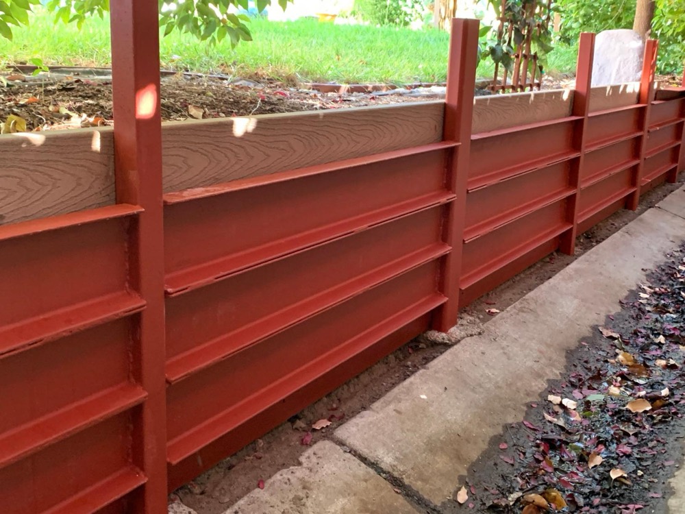 Customer photo of a steel retaining wall beside a garden bed, coated in XionLab red oxide rust converter and primer