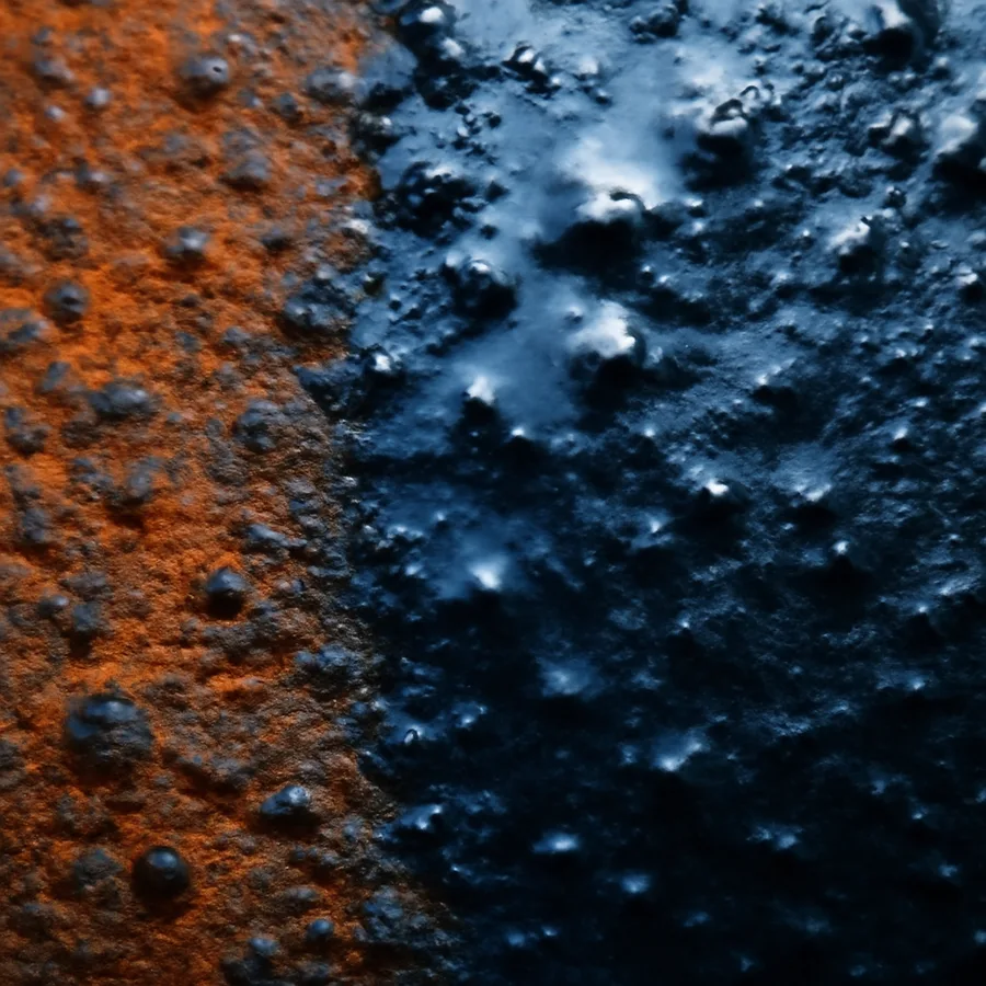 Rust converter curing to a glossy blue black layer across heavily pitted steel surface