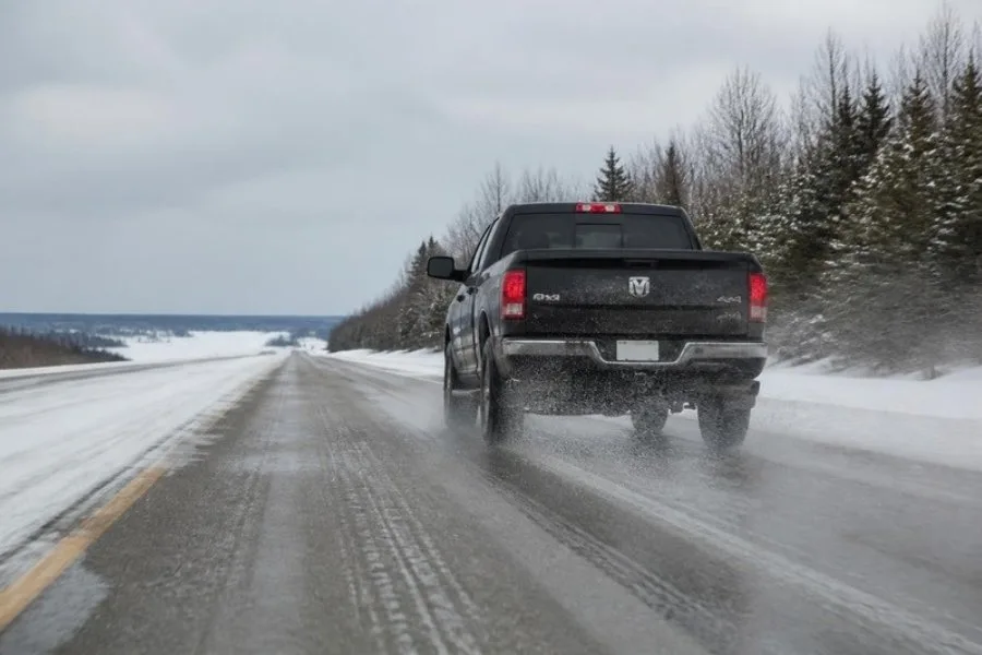 Pickup truck driving through salty slush on winter road, risking frame rust